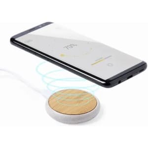 A wireless charger with a wooden base and white padding, charging a black smartphone displaying a battery percentage.