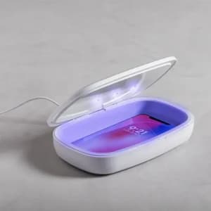A phone sanitiser with a white exterior and a purple interior, featuring a phone inside the unit.