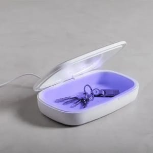 A storage box with a white exterior and purple interior, containing keys and a USB drive, with an open lid.