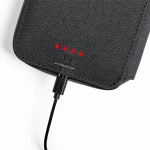 A black portable charger with LED indicators, connected to a charging cable. It has a textured surface and a logo.