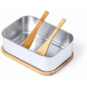 A rectangular metal container with two wooden utensils on a bamboo base. The container is silver in colour.
