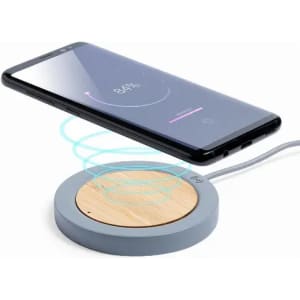A wireless charging pad with a circular grey base and wooden centre, alongside a smartphone displaying a charging indicator.