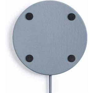 A grey circular wireless charger with four black rubber feet and a connected cable.