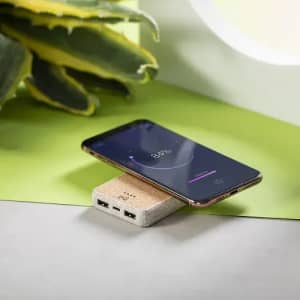 A charging pad and smartphone rest on a surface with green and grey tones, featuring a natural texture.