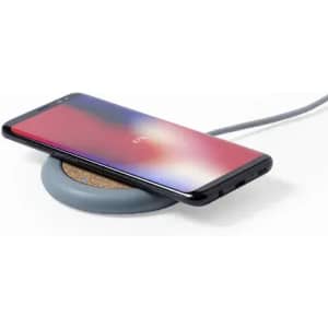A wireless charger with a cork surface and a grey base, holding a smartphone on top.