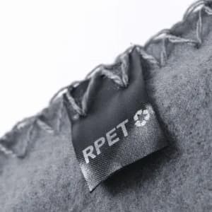 A grey fabric with a stitched edge, featuring a tag that indicates it’s made from RPET material.