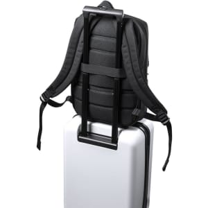 A black backpack secured on top of a white suitcase, featuring adjustable straps and a sleek design.