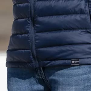 A navy puffer vest with a zippered front and a tag visible at the hem.