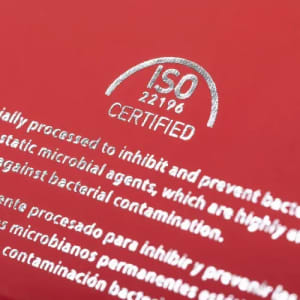A close-up of a red drink bottle featuring a logo and certification text in silver.