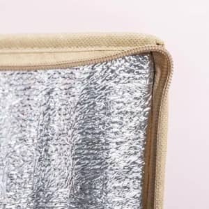 A tan insulated bag with a shiny silver interior, featuring a zip closure edge.