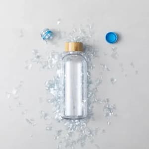 A drink bottle with a wooden lid, surrounded by shards of glass and a blue plastic cap.
