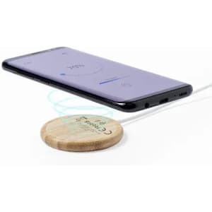 A wooden wireless charging pad with a smartphone hovering above it, displaying a charging indicator on the screen.