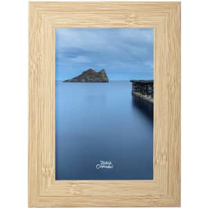 A framed photograph featuring a serene blue landscape with an island and a pier, surrounded by a natural wood frame.