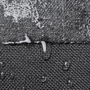 A textured black fabric surface with water droplets beading on top, showcasing its water-resistant properties.