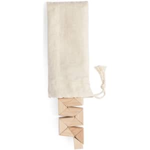 A set of wooden blocks arranged in a stack, with a natural fabric pouch above them.