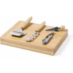 A wooden cutting board with four utensils: a peeler, cheese knife, corkscrew, and bottle stopper.