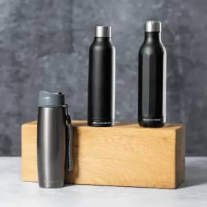 A drink bottle in grey with a lid and two sleek black bottles on a wooden display. All feature a modern design.