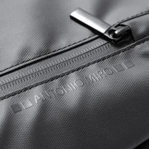 A grey fabric bag featuring a silver zipper and subtle branding on the surface.