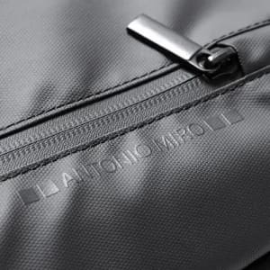 A grey fabric surface with a zipper and an embossed logo. The material has a textured finish.