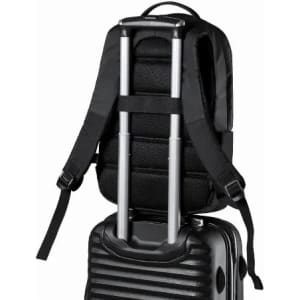 A black backpack with padded straps resting on a rolling suitcase, featuring retractable handles.
