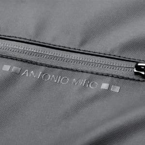 A close-up of a grey fabric with a zipper and the branding of Antonio Miro embossed on the surface.