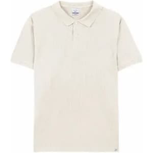A short-sleeved polo shirt in a light beige colour, featuring a collar and a subtle texture. It has a logo on the hem.
