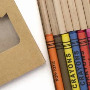 A set of eco-friendly crayons in various colours, packaged in a brown cardboard box with a window.