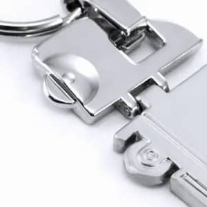 A metallic keyring with a sleek, shiny finish, featuring a unique design and a circular keychain attachment.