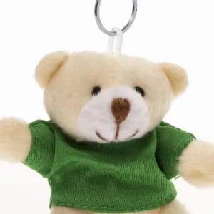 A small teddy bear keychain wearing a green shirt, featuring a smiling face and soft fur.