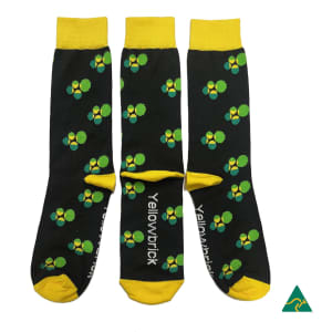 Three pairs of black socks featuring green and yellow floral patterns, with a logo on one side.