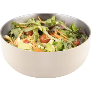 A salad bowl in cream colour, filled with mixed greens, tomatoes, and shredded carrots, with a silver interior.