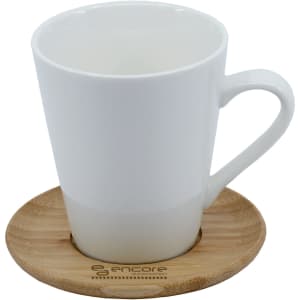 A white ceramic mug with a handle, sitting on a round bamboo saucer. The mug has a smooth, glossy finish.