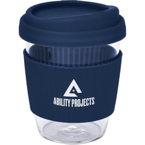A reusable coffee cup in clear glass with a navy blue silicone lid and band, featuring a logo.