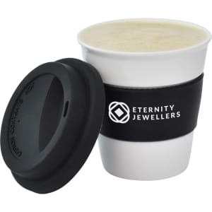 A ceramic coffee mug in white with a black silicone sleeve and lid, featuring a logo.