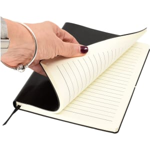 A black A5 notepad with lined pages, partially opened, held in a hand.