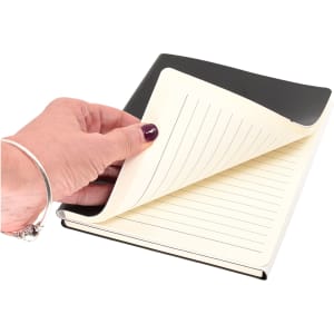 A hand holding the black and white "Two to Tango" A5 notebook, revealing lined pages inside.