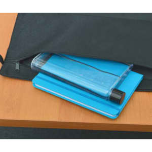 A blue drink bottle with a black lid resting on a blue notepad, placed inside a black bag on a wooden surface.