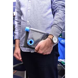 A drink bottle with a transparent design and blue accents, held in a person's hand. It has a logo on the side.