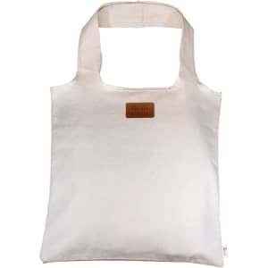 A cream-coloured tote bag made of calico, featuring a logo patch on the front.