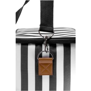 A cooler bag with a black and white striped design, featuring a handle and a tag, and includes a logo.