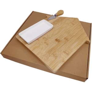 A bamboo cheese board in the shape of a house, featuring a ceramic dish and a knife, packaged in a brown cardboard box.