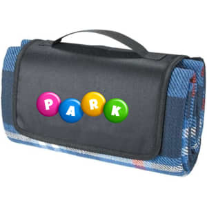 A blue picnic rug with a patterned underside, featuring a black carrying handle and a logo on the front.