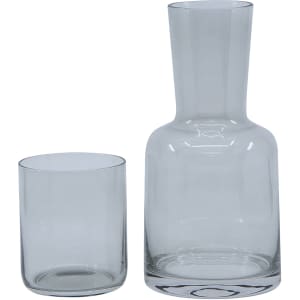 A glass carafe and matching tumbler set in clear glass, featuring a sleek design. The set includes one carafe and one tumbler.