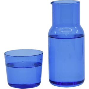 A blue glass carafe next to a matching tumbler, both filled with water. The carafe features a sleek, modern design.