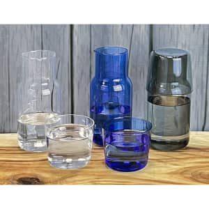 A drink bottle set featuring a clear glass carafe, blue carafe, and matching tumblers in various shades of blue and clear.