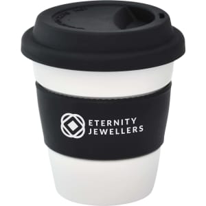 A reusable ceramic mug in white with a black silicone lid and sleeve, featuring a logo.