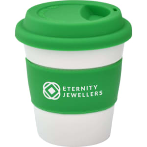 A reusable coffee cup featuring a green silicone lid and sleeve with a white body. The cup has a logo.