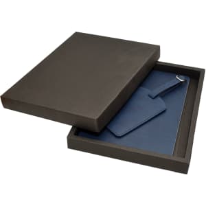 A dark box containing a blue travel journal and matching luggage tag. The items are neatly presented inside the box.