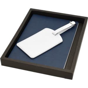 A navy blue travel journal set with a white luggage tag, presented in a black box.