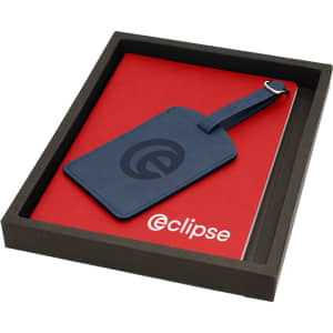 A red journal and a blue luggage tag in a black box, featuring a logo on the tag and journal cover.